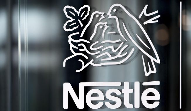 In this Thursday, Feb. 14, 2019, file photo, Nestle&#x27;s logo is displayed on a window, during the 2018 full-year results press conference of the food and drinks giant Nestle, in Vevey. A report published Monday by the non-governmental group CDP found consumer goods giants are working to lower their carbon emissions, prepare for the effects of global warming and respond to growing environmental consciousness among customers. (Laurent Gillieron/Keystone via AP, File)