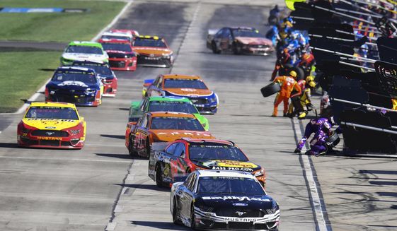 Aric Almirola (10) is followed by Martin Truex Jr. (19) as they and others pit during a NASCAR Monster Energy NASCAR Cup Series auto race at Atlanta Motor Speedway, Sunday, Feb. 24, 2019, in Hampton, Ga. (AP Photo/Scott Cunningham)