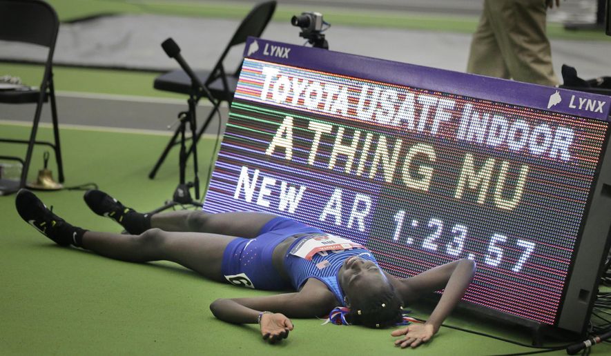 Athing Mu poses for photos in front a digital board displaying her results after she won the women's 600-meter event at the USA Track & Field Indoor Championships in New York, Sunday, Feb. 24, 2019. Mu set an American record by running the race in 1:23.57. (AP Photo/Seth Wenig)