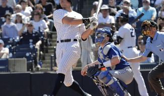New York Yankees&#x27; Aaron Judge, left, follows through on a double in the third inning during a spring training baseball game against the Toronto Blue Jays, Monday, Feb. 25, 2019, in Tampa, Fla. At right is Toronto Blue Jays catcher Danny Jansen. (AP Photo/Lynne Sladky)