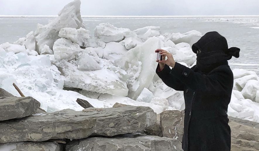 Rose Hirschbeck, of Hamburg, NY, photographs mounds of ice collected along the Lake Erie shore at Hoover Beach, in Hamburg, N.Y., Monday, Feb. 25, 2019. High winds howled through much of the nation's eastern half for a second day Monday, cutting power to hundreds of thousands of homes and businesses, closing schools, and pushing dramatic mountains of ice onto the shores of Lake Erie. (AP Photo/Carolyn Thompson)