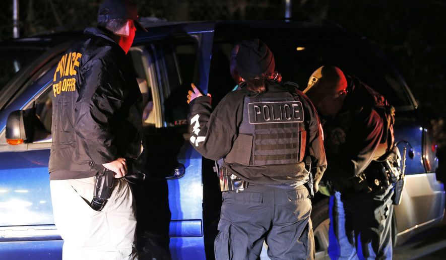 In this Oct. 22, 2018, photo U.S. Immigration and Customs Enforcement agents surround and detain a person during a raid in Richmond, Va. ICE's enforcement and removal operations, like the five-person field office team outside Richmond, hunt people in the U.S. illegally, some of whom have been here for decades, working and raising families. Carrying out President Donald Trump's hard-line immigration policies has exposed ICE to unprecedented public scrutiny and criticism, even though officers say they're doing largely the same job they did before the election, prioritizing criminals. (AP Photo/Steve Helber)