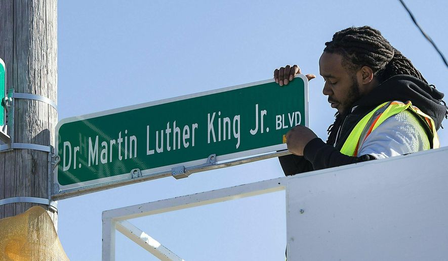 In this Monday, Feb. 25, 2019 photo, DeAnthony Jackson installs the first new Dr. Martin Luther King, Jr. Boulevard street sign, at 34th Street and The Paseo, in Kansas City, Mo. The City Council voted last month to rename a 10-mile stretch of The Paseo after the civil rights leader. (Tammy Ljungblad/The Kansas City Star via AP)