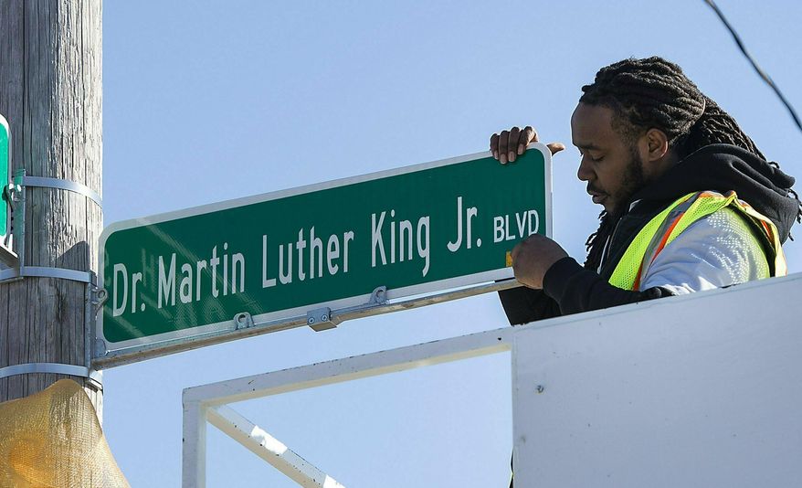 In this Monday, Feb. 25, 2019 photo, DeAnthony Jackson installs the first new Dr. Martin Luther King, Jr. Boulevard street sign, at 34th Street and The Paseo, in Kansas City, Mo. The City Council voted last month to rename a 10-mile stretch of The Paseo after the civil rights leader. (Tammy Ljungblad/The Kansas City Star via AP)