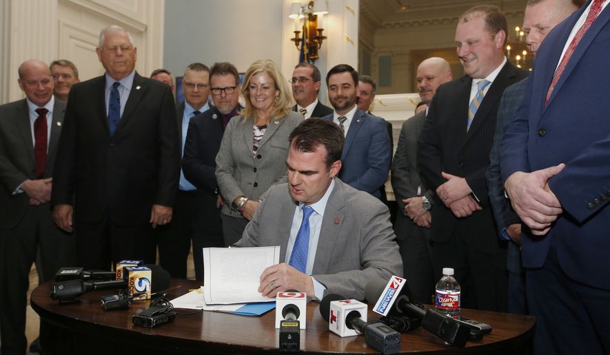 Oklahoma Gov. Kevin Stitt signs the permitless carry bill into law, as legislators look on,  Wednesday, Feb. 27, 2019, in Oklahoma City. (AP Photo/Sue Ogrocki)