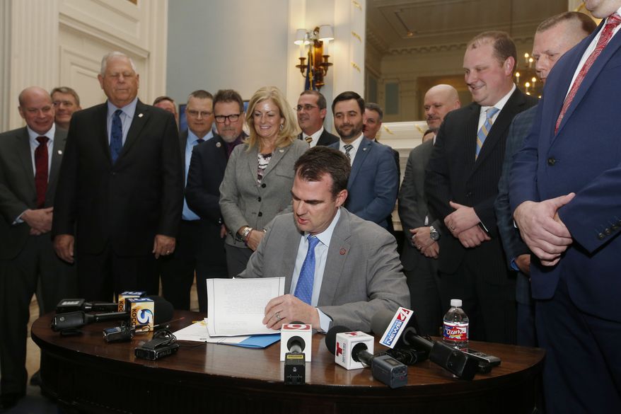 Oklahoma Gov. Kevin Stitt signs the permitless carry bill into law, as legislators look on, Wednesday, Feb. 27, 2019, in Oklahoma City. (AP Photo/Sue Ogrocki)