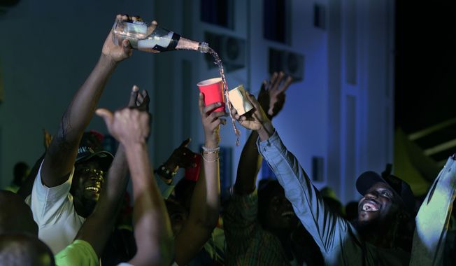 Supporters of Incumbent President Muhammadu Buhari pour champagne anticipating a win as they wait for the results to be officially announced in Abuja, Nigeria, Tuesday, Feb. 26, 2019. Anxious Nigerians on Tuesday awaited a second day of state-by-state announcements of presidential election results in a race described as too close to call. Buhari is facing opposition presidential candidate Atiku Abubakar. (AP Photo/Jerome Delay)
