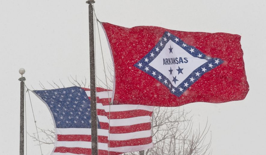 FILE - In this Feb. 1, 2011 file photo, an American and Arkansas flag blow in the wind as snow falls in Fayetteville, Ark. A legislative panel has rejected a proposal Wednesday, Feb. 27, 2019, to strip the Confederate designation from one of the stars on Arkansas' flag and instead have it represent the contributions of Native Americans in the state. (AP Photo/Beth Hall, File)