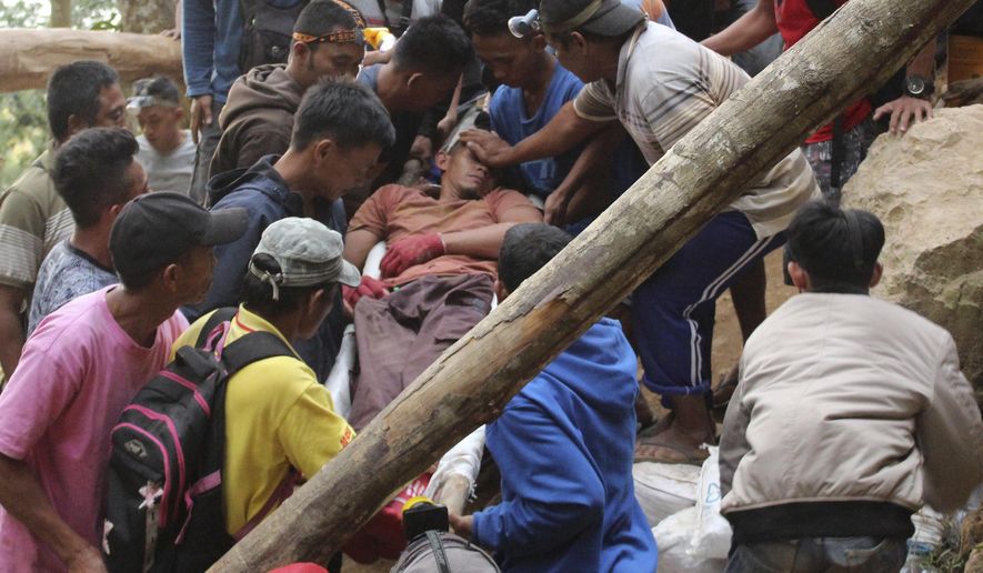 Rescuers carry a survivor from inside a collapsed mine in Bolaang Mongondow, North Sulawesi, Indonesia, Wednesday, Feb. 27, 2019. The collapse of an unlicensed gold mine in Indonesia buried dozens of people, and rescuers dug desperately with their bare hands and farm tools on Wednesday to unearth victims calling for help from beneath the rubble. (AP Photo/Harry Tri Atmojo)
