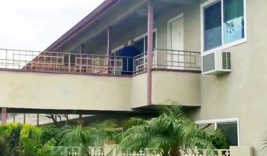 In this still image taken from video, an investigator is seen at the apartment building where authorities say a mother threw her young son from a second-story apartment landing and jumped herself as police arrived in Upland, Calif., Tuesday, Feb. 26, 2019. The mother and 1-year-old boy were hospitalized in stable condition, police said. A baby girl was found dead inside their apartment. (Beatriz Valenzuela/The Orange County Register/SCNG via AP)