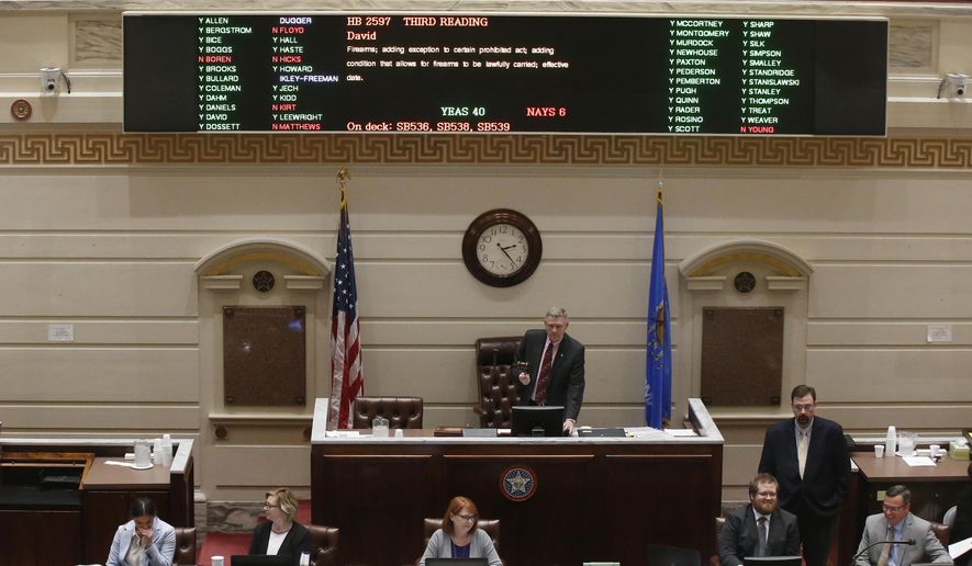 Oklahoma state Sen. Gary Stanislawski, R-Tulsa, stands under the voting board as the vote is counted on the permitless carry bill on the Senate floor Wednesday, Feb. 27, 2019, in Oklahoma City. (AP Photo/Sue Ogrocki)