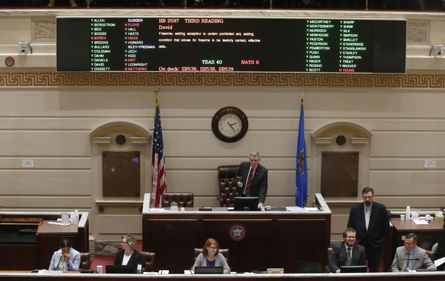 Oklahoma state Sen. Gary Stanislawski, R-Tulsa, stands under the voting board as the vote is counted on the permitless carry bill on the Senate floor Wednesday, Feb. 27, 2019, in Oklahoma City. (AP Photo/Sue Ogrocki)