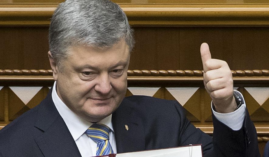 FILE - In this file photo dated Tuesday Feb. 19, 2019, Ukrainian President Petro Poroshenko shows the newly signed Constitutional amendment to joining the EU and NATO in Ukrainian parliament in Kiev, Ukraine. President Petro Poroshenko said he would instruct his government to formulate a new draft law on punishing officials for corruption and that it would be submitted to parliament as an urgent priority. (Mikhail Palinchak, Presidential Press Service Pool Photo via AP, File)