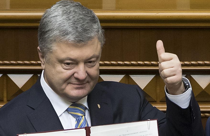 FILE - In this file photo dated Tuesday Feb. 19, 2019, Ukrainian President Petro Poroshenko shows the newly signed Constitutional amendment to joining the EU and NATO in Ukrainian parliament in Kiev, Ukraine. President Petro Poroshenko said he would instruct his government to formulate a new draft law on punishing officials for corruption and that it would be submitted to parliament as an urgent priority. (Mikhail Palinchak, Presidential Press Service Pool Photo via AP, File)