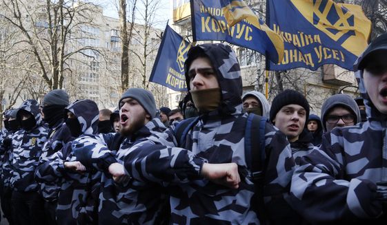 Volunteers with the right-wing paramilitary Azov National Corps shout slogan during a rally in front of the office of the General Prosecutor of Ukraine in Kiev, Ukraine, Wednesday, Feb. 27, 2019. President of Ukraine Petro Poroshenko suspended from office Oleh Hladkovsky, First Deputy Secretary of the National Security and Defense Council, pending the probe opened following a journalistic investigative report on corruption. (AP Photo/Efrem Lukatsky)
