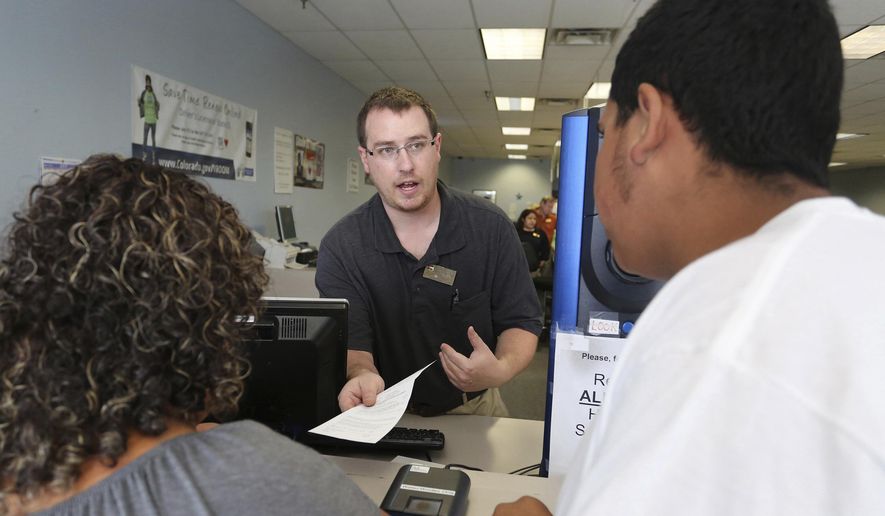 In this Aug. 1, 2014, file photo, an immigrant and longtime resident of the United States, left, is processed for her permanent driver's license at a Department of Motor Vehicles office in Denver. On Thursday, Feb. 28, 2019, Colorado lawmakers are poised to consider a bill to expand the program that issues state driver's licenses to immigrants in the country illegally, a measure Republicans have stopped in previous attempts. (AP Photo/Brennan Linsley, File)