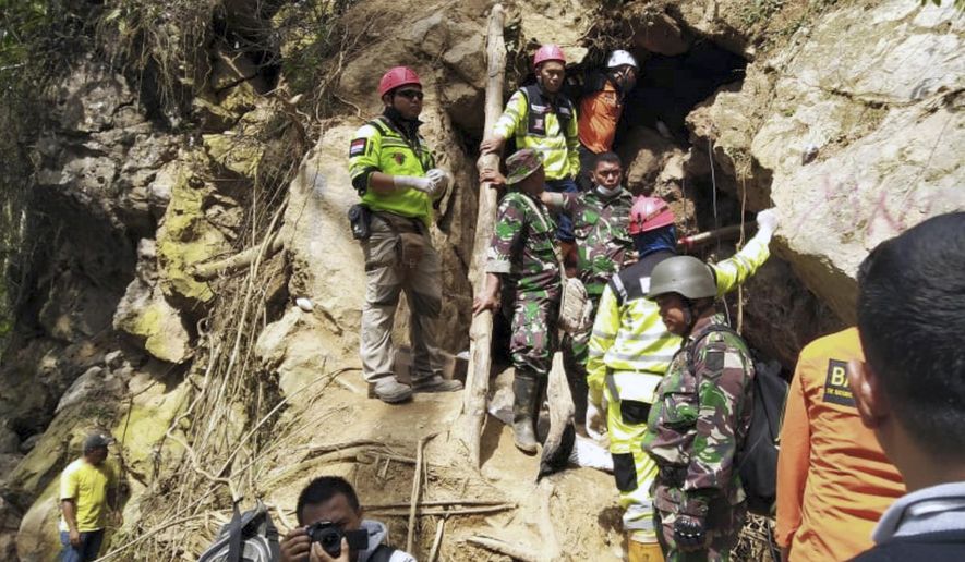 Rescuers stand at the entrance of a collapsed mine in Bolaang Mongondow, North Sulawesi, Indonesia, Thursday, Feb. 28, 2019. Rescue workers used makeshift stretchers to haul victims of the gold mine collapse through steep jungle terrain to safety, as the death toll rose and dozens remained trapped in the debris. (AP Photo)