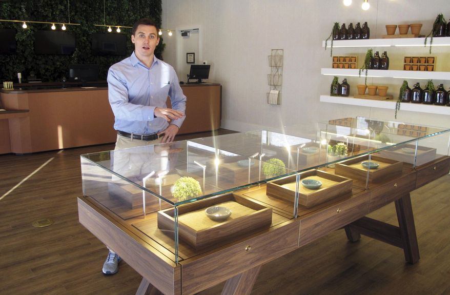 Pat Doherty, director of new market development for Acreage Holdings, describes products inside a display case at The Botanist in Fargo, N.D., Thursday, Feb. 28, 2019. The business located in a south-side mini-mall is North Dakota's first medical marijuana dispensary. North Dakota voters approved the drug in November 2016, after lawmakers refused to do it. (AP Photo/Dave Kolpack)