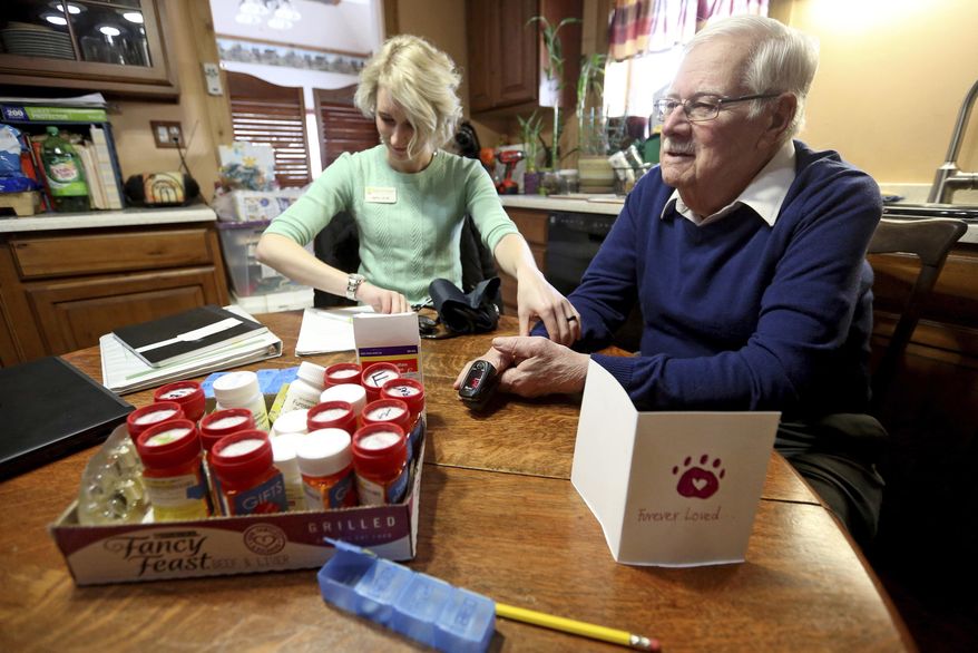 In this Jan. 25, 2019, photo, Kristin Schroeder, a Hospice of Dubuque nurse, takes vitals on Paul "Jack" Papin during a visit at his home in Dubuque, Iowa. (Jessica Reilly/Telegraph Herald via AP)