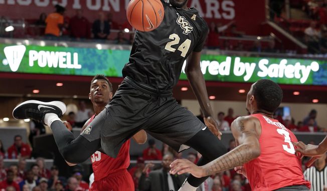 Central Florida center Tacko Fall (24) dunks over, from left to right, Houston forward Brison Gresham (55), forward Breaon Brady and guard Armoni Brooks (3) during the first half of an NCAA college basketball game Saturday, March 2, 2019, in Houston. (AP Photo/Michael Wyke)