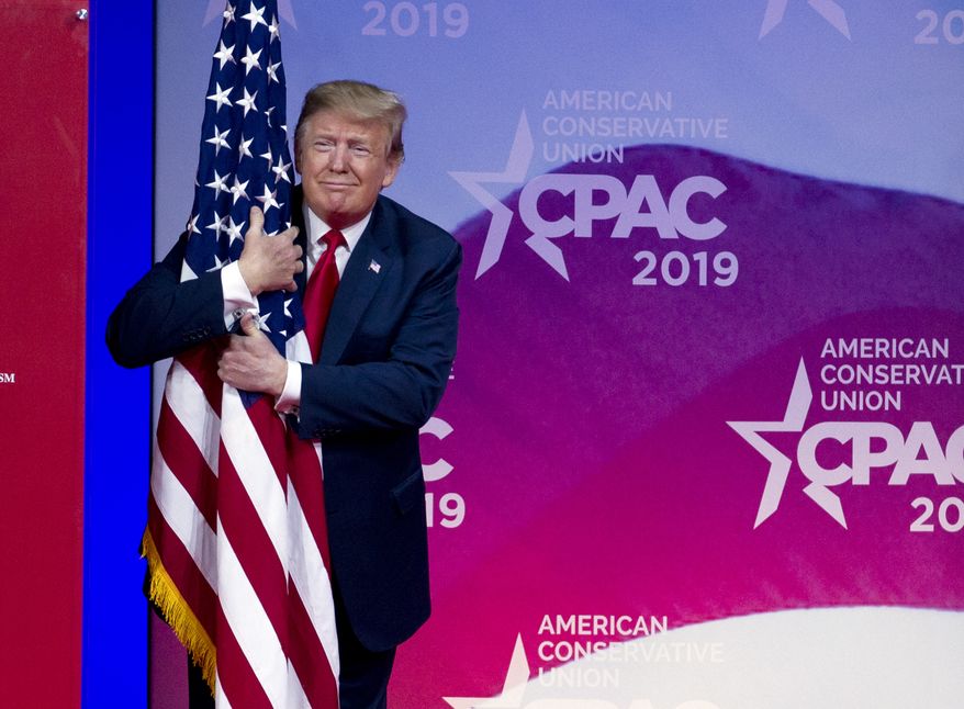 President Donald Trump hugs the American flag as he arrives to speak at Conservative Political Action Conference, CPAC 2019, in Oxon Hill, Md., Saturday, March 2, 2019. (AP Photo/Jose Luis Magana)