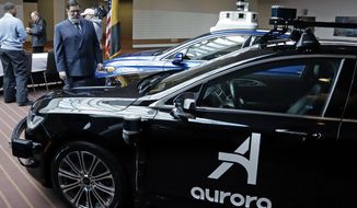 Pittsburgh Mayor William Peduto, left, checks out autonomous vehicles designed by Aurora Innovations, front, and Argo AI, rear, after signing an executive order outlining objectives and expectations for the safe testing and development of autonomous vehicles in Pittsburgh, Monday, March 4, 2019. (AP Photo/Gene J. Puskar)