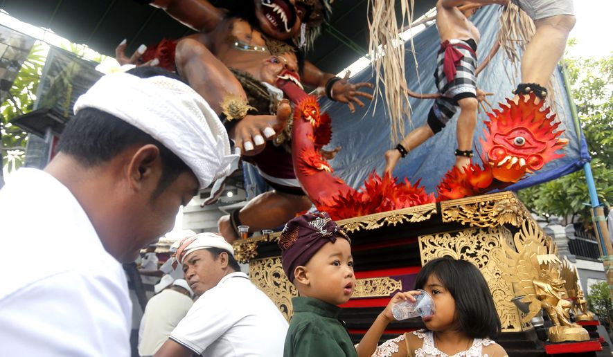 Balinese people sit in front of a giant effigy locally known as "ogoh-ogoh" that represents evil spirits to celebrate Nyepi, the annual day of silence marking Balinese Hindu new year in Bali, Indonesia, Wednesday, March 6, 2019. Most Balinese practice self-reflection and stay at home to observe the quiet holiday, and tourists visiting the island are asked not to leave their hotels and the airport will be closed. (AP Photo/Firdia Lisnawati)