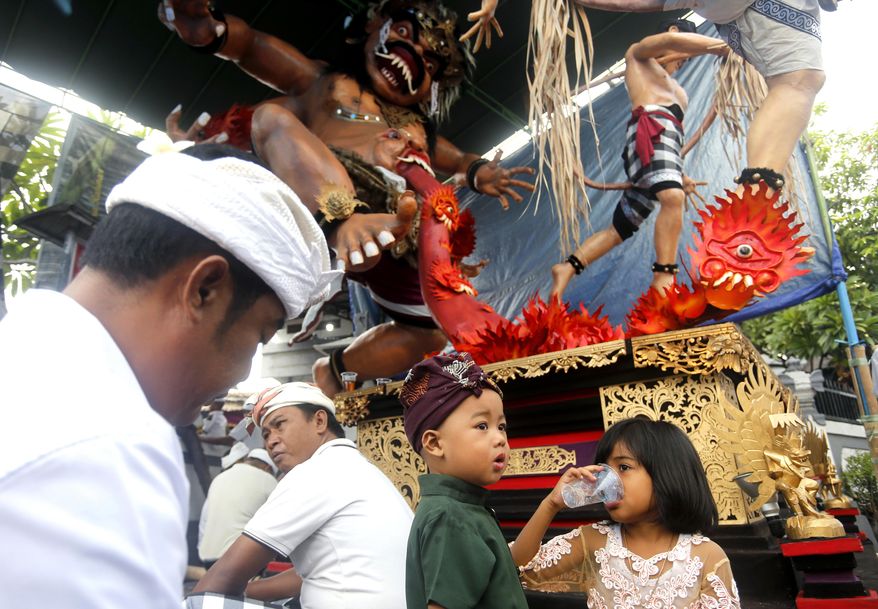 Balinese people sit in front of a giant effigy locally known as "ogoh-ogoh" that represents evil spirits to celebrate Nyepi, the annual day of silence marking Balinese Hindu new year in Bali, Indonesia, Wednesday, March 6, 2019. Most Balinese practice self-reflection and stay at home to observe the quiet holiday, and tourists visiting the island are asked not to leave their hotels and the airport will be closed. (AP Photo/Firdia Lisnawati)