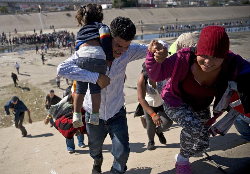 In this Nov. 25, 2018, photo, migrants walk up a riverbank at the Mexico-U.S. border after getting past a line of Mexican police at the Chaparral border crossing in Tijuana, Mexico, as they try to reach the U.S. A San Diego TV station says the U.S. government ran an operation to screen journalists, activists and others while investigating last year's migrant caravan from Mexico. KNSD-TV says documents leaked by a Homeland Security source show a January database listing at least 10 journalists, seven of them U.S. citizens, as warranting secondary screening at U.S. points of entry. (AP Photo/Ramon Espinosa) **FILE**
