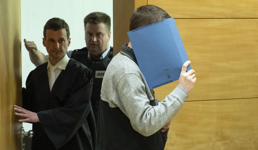 A 57-year old defendant hides his face at the courtroom in Bielefeld, Germany, Thursday, March 7, 2019. A judge in Germany has found the man guilty of poisoning his co-workers' sandwiches with mercury, lead acetate and other chemicals over several years and sentenced him to life in prison. (Friso Gentsch/dpa via AP)