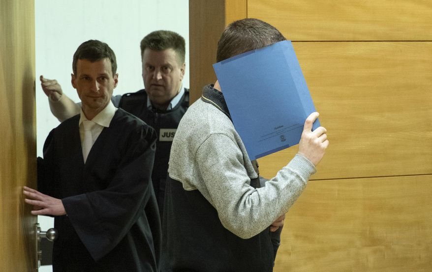 A 57-year old defendant hides his face at the courtroom in Bielefeld, Germany, Thursday, March 7, 2019. A judge in Germany has found the man guilty of poisoning his co-workers' sandwiches with mercury, lead acetate and other chemicals over several years and sentenced him to life in prison. (Friso Gentsch/dpa via AP)