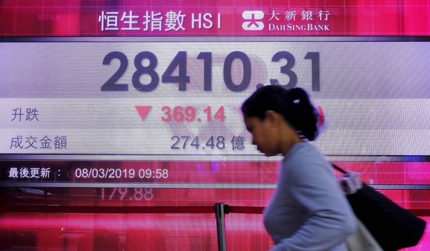 A woman walks past an electronic board showing Hong Kong share index outside a local bank in Hong Kong, Friday, March 8, 2019. Asian markets tumbled Friday on fears that the U.S. and China may not be as close to a trade deal as President Donald Trump hopes. Selling was also fueled by worries about the global economy ahead of Chinese trade data.(AP Photo/Vincent Yu)