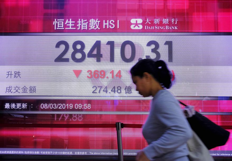 A woman walks past an electronic board showing Hong Kong share index outside a local bank in Hong Kong, Friday, March 8, 2019. Asian markets tumbled Friday on fears that the U.S. and China may not be as close to a trade deal as President Donald Trump hopes. Selling was also fueled by worries about the global economy ahead of Chinese trade data.(AP Photo/Vincent Yu)
