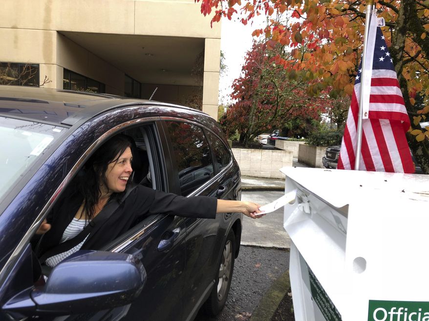 FILE - In this Nov. 6, 2018 file photo, a voter in Lake Oswego, Ore., places her ballot in a designated drop box outside City Hall. Days before last November's elections, members of a political action committee in Oregon went door-to-door in Portland and its suburbs and collected filled-in ballots from voters, saying they'd mail them in. But about 100 of those ballots were mailed late and not counted. The group was fined by the secretary of state (AP Photo/Gillian Flaccus, File)