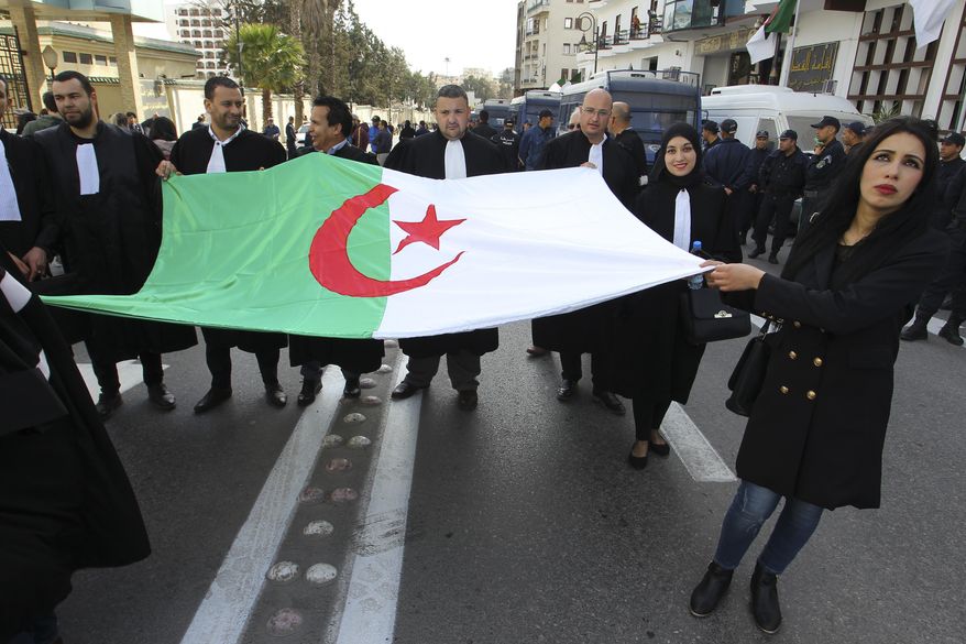Algerian lawyers carrying their national flag march to the constitutional council in a protest against President Abdelaziz Bouteflika, Thursday March 7, 2019 in Algiers. The Algerian leader, in power since 1999 and all but invisible since a stroke in 2013, is running for a fifth term. (AP Photo/Anis Belghoul)