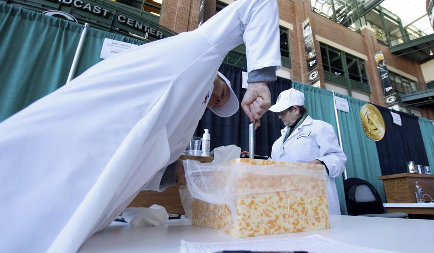 Judge Ben Novak attempts to obtain a piece of marbled curd cheese Tuesday, March 5, 2019 at the United States Championship Cheese Contest in Green Bay, Wis. The three-day event includes more cheese, butter and yogurt makers than ever before. It's is considered the largest technical cheese, butter and yogurt competition in the country. (AP Photo/Carrie Antlfinger)
