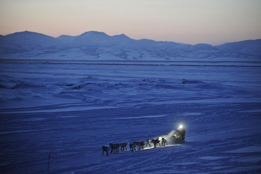 FILE - In this on March 11, 2012 file photo, Dallas Seavey pulls in to the checkpoint in Unalakleet, Alaska, during the Iditarod Trail Sled Dog Race. As of Friday, March 8, 2019, 51 mushers are traveling long stretches between remote village checkpoints with no other company but the dogs pulling their sleds. Their progress is monitored from several hotel rooms in Anchorage, Alaska, whose 24/7 occupants are the Iditarod’s electronic eyes and ears. (Marc Lester/Anchorage Daily News via AP, File)