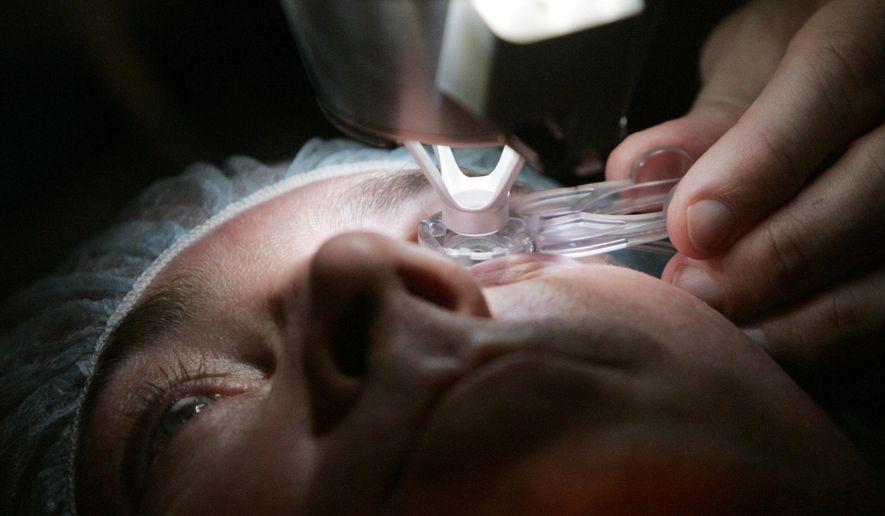 FILE - In this Nov. 1, 2005 file photo, a doctor prepares a patient for Lasik surgery in Chicago. On Friday, March 8, 2018, The Associated Press has found that stories circulating on the internet that elective Lasik surgery is offered to all female migrants to the U.S. in family detention, and children given braces, all no cost, are untrue. (AP Photo/Charles Rex Arbogast)