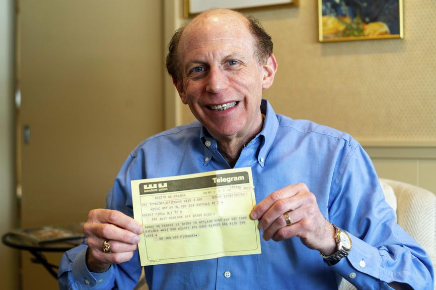 In a Friday, March 1 2019 photo, Robert Fink holds up a telegram from a family friend congratulating him on his 1969 graduation from the University of Michigan at his home in Huntington Woods, Mich. The telegram, delivered to his apartment the day after he moved away from Ann Arbor, was recovered 50 years later by an employee of a downtown Ann Arbor company in a filing cabinet bought from the University of Michigan. (Jacob Hamilton/Ann Arbor News via AP)