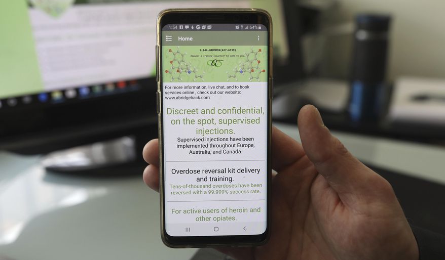 This Feb. 21, 2019 photo shows Lucien Izraylov, an addiction counselor and former heroin user, holds his phone with an open app he created in his office in Evanston, Ill. The smartphone app is design to connect drug users with volunteers who will make sure they don't overdose. (Abel Uribe/Chicago Tribune via AP)
