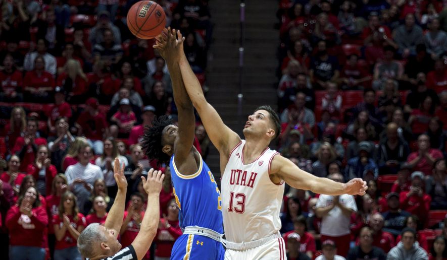 UCLA guard Jalen Hill, center, and Utah forward Novak Topalovic (13) jump for the ball in the first half of an NCAA college basketball game Saturday, March 9, 2019, in Salt Lake City. (AP Photo/Tyler Tate)