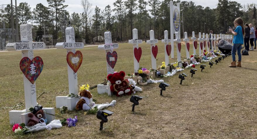 Katie Nobles photographs crosses representing the 23 lives lost in the tornado that hit the Beauregard community on March 3, to share with her friend who was injured in the storm and lost loved ones, Sunday, March 10, 2019, at Providence Baptist Church in Beauregard, Ala. Nobles' friend Kayla Grimes lost family members to the storm and is still recovering from serious injuries in a Birmingham hospital. (AP Photo/Vasha Hunt)