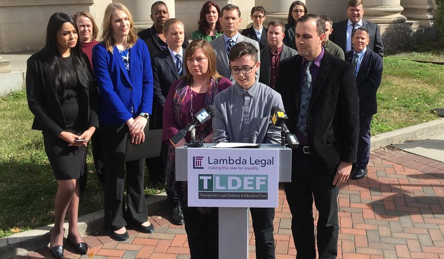 Connor Thonen-Fleck addresses reporters while his parents stand by his side on Monday March 11, 2019, in Durham, North Carolina at the announcement of a lawsuit against North Carolina officials over how the state health plan is run. The lawsuit argues that North Carolina's state health plan for state employees discriminates by not covering hormone treatment and surgery for transgender people. (AP Photo/ Jonathan Drew)