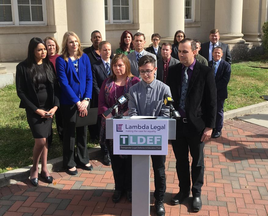 Connor Thonen-Fleck addresses reporters while his parents stand by his side on Monday March 11, 2019, in Durham, North Carolina at the announcement of a lawsuit against North Carolina officials over how the state health plan is run. The lawsuit argues that North Carolina's state health plan for state employees discriminates by not covering hormone treatment and surgery for transgender people. (AP Photo/ Jonathan Drew)