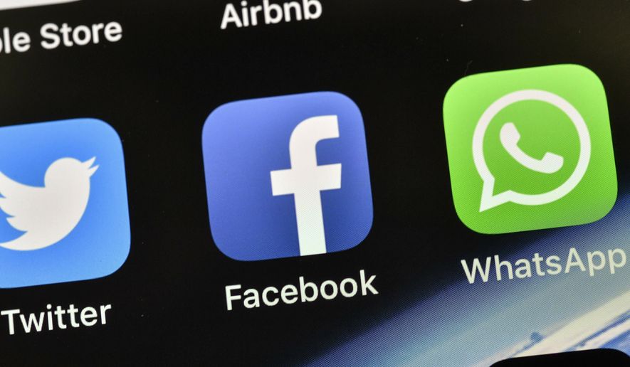 FILE - In this Nov. 15, 2018, file photo the icons of Facebook and WhatsApp are pictured on an iPhone in Gelsenkirchen, Germany. Facebook is already the leader in enabling you to share photos, videos and links. It now wants to be a force in messaging, commerce, payments and just about everything else you do online. (AP Photo/Martin Meissner, File)