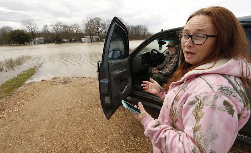 In this Monday, March 11, 2019 photo, Peggy and her husband George Sellars sit by the "lake" that was the driveway to their home, along Mississippi 16, east of Rolling Fork, Miss. The couple said the backwater flooding is the worse they have encountered and correctly concluded that water would overtop the retention levee that protected their house and three others. This week the Federal Emergency Management Agency (FEMA), the Mississippi Emergency Management Agency (MEMA), along with select local emergency management offices will be conducting joint damage assessments in response to the severe storms and flooding are impacting the state. (AP Photo/Rogelio V. Solis)