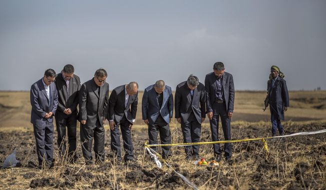 Officials from the Aviation Industry Corporation of China (AVIC) pray next to an offering of fruit, bread rolls, and a plastic container of Ethiopian Injera, a fermented sourdough flatbread, placed next to incense sticks, at the scene where the Ethiopian Airlines Boeing 737 Max 8 crashed shortly after takeoff on Sunday killing all 157 on board, near Bishoftu, or Debre Zeit, south of Addis Ababa, in Ethiopia Tuesday, March 12, 2019. Ethiopian Airlines had issued no new updates on the crash as of late afternoon Tuesday as families around the world waited for answers, while a global team of investigators began picking through the rural crash site. (AP Photo/Mulugeta Ayene) **FILE**