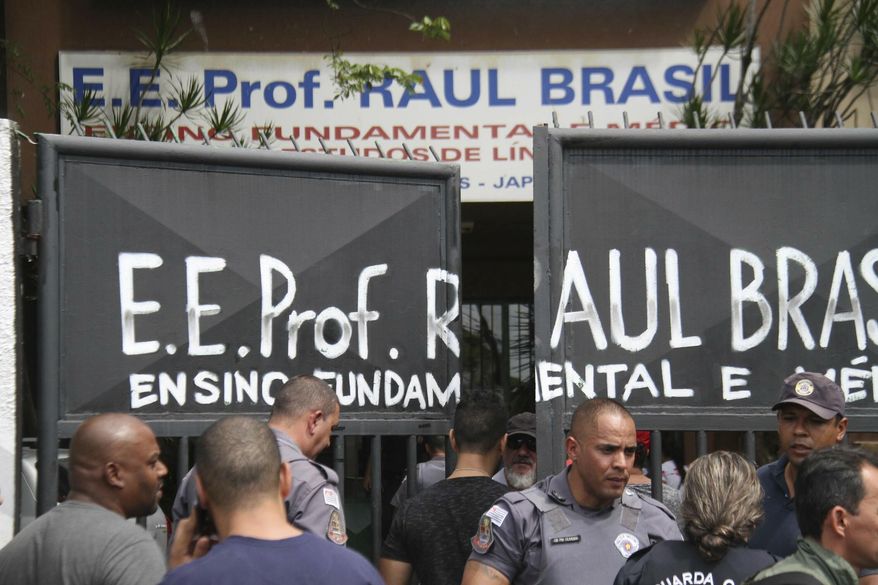 Police officers guard the entrance of the Raul Brasil State School in Suzano, Brazil, Wednesday, March 13, 2019. The state government of Sao Paulo said two teenagers, armed with guns and wearing hoods, entered the school and began shooting at students. They then killed themselves, according to the statement. (Mauricio Sumiya/Futura Press via AP)