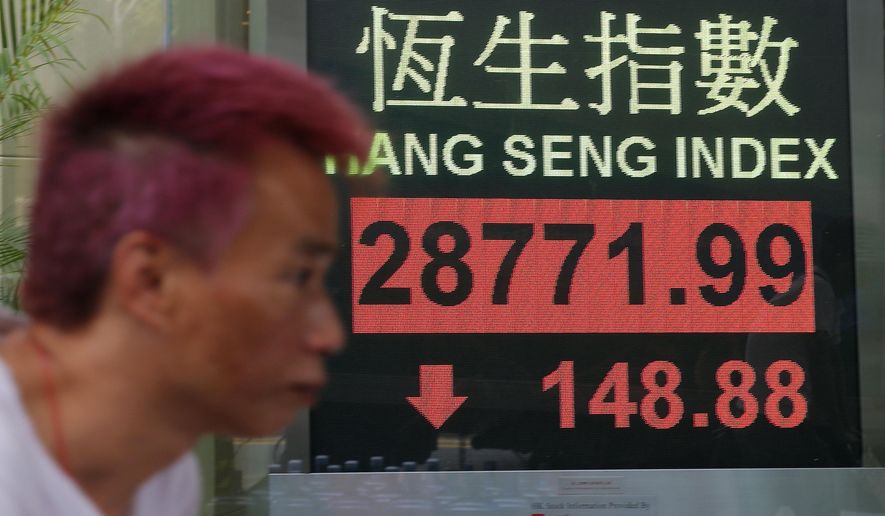 A man walks past an electronic board showing Hong Kong share index outside a bank in Hong Kong, Wednesday, March 13, 2019. Asian shares were lower Wednesday amid continuing global uncertainties that weighed on stocks as some traders took profits from a rally earlier in the week. (AP Photo/Kin Cheung)