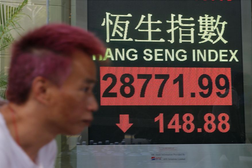 A man walks past an electronic board showing Hong Kong share index outside a bank in Hong Kong, Wednesday, March 13, 2019. Asian shares were lower Wednesday amid continuing global uncertainties that weighed on stocks as some traders took profits from a rally earlier in the week. (AP Photo/Kin Cheung)